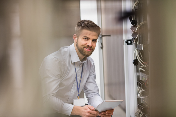 Portrait of technician using digital tablet while analyzing server in server room